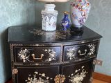une commode noire sur laquelle est posée une lampe