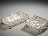 two silver plated trays with handles and handles on a table