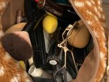 un sac à main rempli de maquillage et d'autres objets, posé par terre