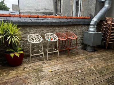 trois chaises posées sur une terrasse en bois, à côté d'une plante en pot