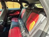 the interior of a car with red leather seats and a laptop on the back seat