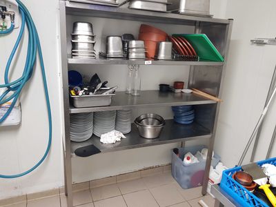 une étagère métallique avec des casseroles et des poêles dans une cuisine