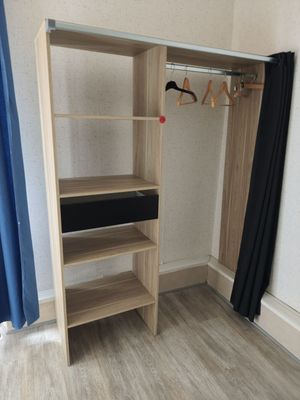 a wooden closet with a shelf and a blue curtain in the corner