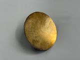 a gold object on a gray surface with a white background
