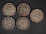 quatre vieilles pièces de monnaie sont posées sur une table devant un fond noir