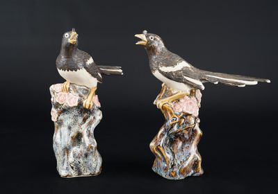 two figurines of birds sitting on top of a tree stump