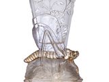 un vase en verre orné d'un insecte, posé sur un socle