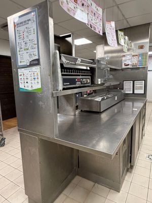 stainless steel counter top in a commercial kitchen with menus hanging from the ceiling