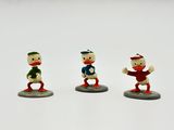 trois figurines de trois personnages différents sur une surface blanche