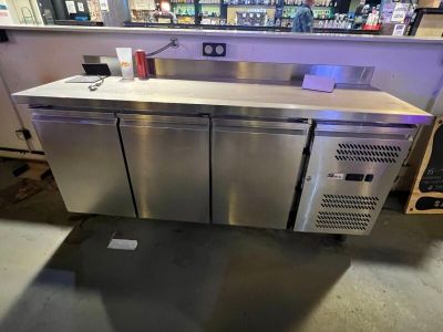 a stainless steel counter in a store with a lot of bottles on it
