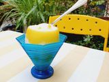 a yellow and blue bowl with a spoon in it on a table