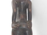 an image of a wooden statue of a man sitting on a chair