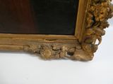 une image représentant un tableau d'une femme, dans un cadre doré, posé sur une surface blanche