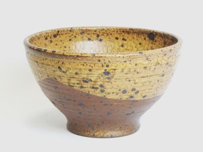 a brown and black bowl sitting on a white surface