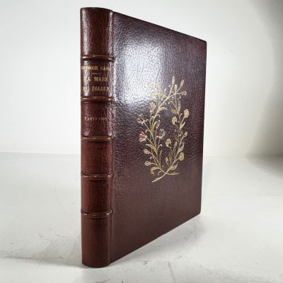 un vieux livre à la couverture marron posé sur une table blanche