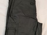 un pantalon cargo vert foncé posé sur un drap blanc sur un lit