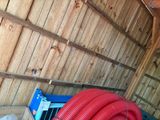 a red hose that is next to a wooden wall