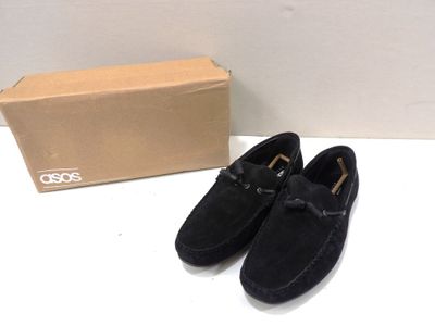 mocassins en daim noir pour homme, avec des boucles, posés sur une table