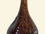 a brown vase with a green top on a white surface