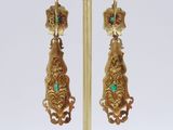 pair of gold and emerald earrings on a gold stand