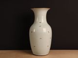 a white vase sitting on a table against a black wall