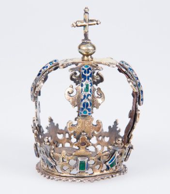 une couronne richement décorée, surmontée d'une croix, posée sur un fond blanc
