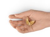 a person holding a gold leaf brooch in their hand