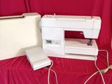 une machine à coudre blanche posée sur un tissu rouge