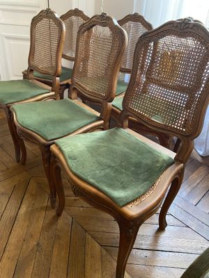 four chairs with green upholstered cushions sit on a wooden floor