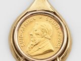 a close up of a coin in a gold pendant on a white background
