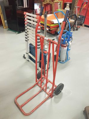 a red hand truck with a stack of ladders on it