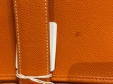 an orange leather bag with a white tag on it
