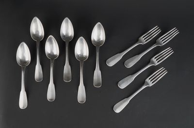 a group of silver spoons and forks on a black surface