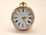une petite montre de poche en or avec des chiffres romains