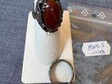 une bague avec une pierre rouge posée sur un morceau de plastique