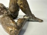 a bronze statue of a man laying on his stomach