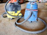 two vacuums that are on the ground in the garage