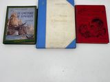 three books are lined up on a table with a white background