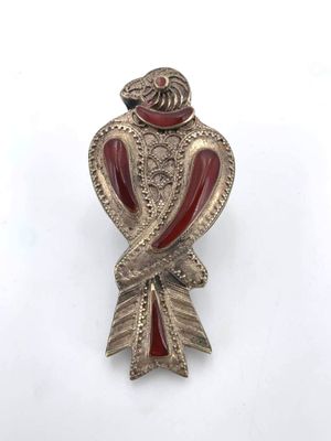 a close up of a bird broochle on a white surface