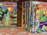 Trois albums de BD sont alignés sur un lit à tête de lit en bois