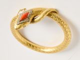a close up of a gold bracelet with a red stone in the middle