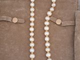 a close up of a necklace with pearls and a gold clasp