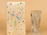 un petit vase en verre posé à côté d'une petite boîte ornée d'un motif en forme d'étoile