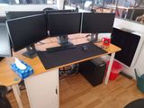 three computer monitors on a desk in a room