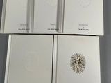 four books with white covers sitting on top of a table