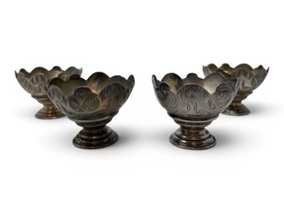 four metal bowls sitting on top of each other on a white surface