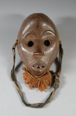 un vieux masque en bois au visage brun, suspendu à une ficelle