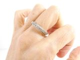 a woman ' s hand holding a diamond ring on a white surface