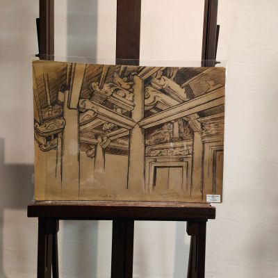 painting on a wooden easel in a room with a white wall