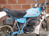 a blue and white motorcycle parked in front of a brick wall